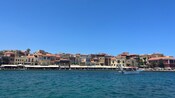 A seaside town with rows of buildings and outdoor seating areas along the waterfront overlooking the sea