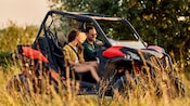 Two Guests riding in a dune buggy through a grassy field