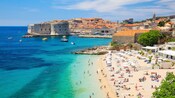 Una playa concurrida junto a la histórica ciudad amurallada de Dubrovnik, Croacia
