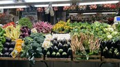 Puesto de mercado con verduras frescas, incluidas berenjenas, verduras de hoja verde, coliflor y otros productos agrícolas