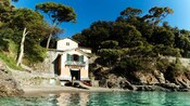 A house on a rocky shore near trees and water in Portofino, Italy