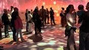 Guests standing in a room and watching projections of art on the walls