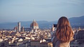 Una mujer fotografiando el paisaje urbano de Florencia, incluida la catedral del Duomo y las montañas
