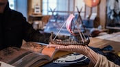 A hand holding a miniature replica of a Viking ship at a Viking museum