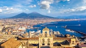 Aerial panoramic view of Naples Bay and Mount Vesuvius with a church bell tower and multiple ports with ships