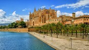 The Cathedral of Santa Maria of Palma looming over palm trees and a saltwater lake in Mallorca