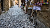 A cobblestone street in the Old Town of Rhodes with a bicycle beside a shop