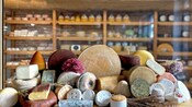 A pile of various cheeses on a table at a cheese shop