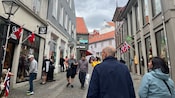 Pedestrians walking along a cobblestone street lined with shops and buildings in Bergen, Norway