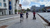 A Guest riding a Segway on a pathway next to a harbor.