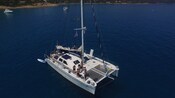 Guests standing on the deck of a sailing catamaran, anchored off the coast of the French Riviera