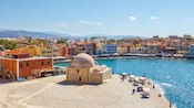 Buildings along a waterfront with a domed stone structure in the center in Chania, Greece