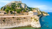 An ancient stone fortress with a lighthouse on top of a rocky cliff overlooking the sea