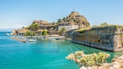 A hilltop fortress made of stone overlooking the harbor with sailboats