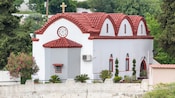 A chapel in Rhodes featuring a tiled arched roof with a cross on top