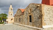 The stone façade of a church near Akramitis Mountain in Rhodes, Greece, with arched doorways and windows  