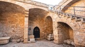 A historic stone courtyard featuring an ornate mosaic floor, arched passageways and weathered walls in Rhodes, Greece