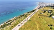 Aerial view of a coastal road in Rhodes overlooking clear waters and a seaside city in the distance