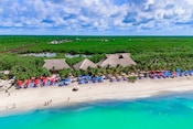 Aerial view of Kuza Beach featuring clear waters, a beach, palm trees and thatched roof buildings
