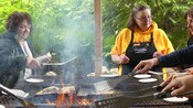 A small group preparing fresh fish on an outdoor grill