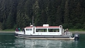 A boat cruising through calm waters in Icy Strait, Alaska