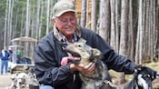 A man petting a couple of harnessed sled dogs