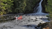 Una lancha motora con dos pasajeros flotando en las aguas cerca de una cascada en Ketchikan, Alaska