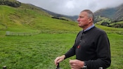Ross, one of the owners of Manderley Farm, standing in front of a grassy field with hills in the background