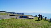 Two people near a gun emplacement with a mural at Godley Head