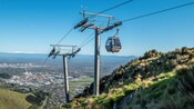 A passenger cable car ascending the hill with a panoramic view of Christchurch in the distance