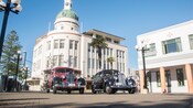 Vintage cars parked in front of an art deco building with a domed clock tower