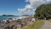 Two Guests walking on a coastal path beside rocky shoreline and ocean waves