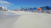 A series of lounge chairs and umbrellas on the shore of a sandy beach
