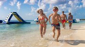 A young family of 4 running and walking on the shore of a sandy beach
