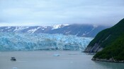 A small boat in Alaska’s Disenchantment Bay surrounded by the sloping peaks of the Hubbard Glacier