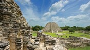 The ruins of a Mayan structure next to a Mayan pyramid