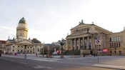 A city square with a stately columned building and a decorative domed cathedral