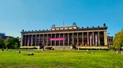 The columned entrance of the Old Museum in Berlin overlooking a grassy lawn