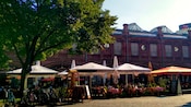 A pedestrian street with people dining at umbrella covered tables