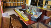 A wooden table with glasses and liquor bottles at a rum shop in Saint John’s