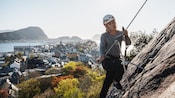 A man rappelling down the face of a steep mountain