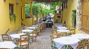 An outdoor café with tables nestled in an alleyway with a decorative arbor