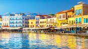 Uma fileira de edifícios em estilo veneziano com restaurantes e cafés abaixo deles, alinhados junto a um porto