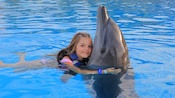 A girl hugs a dolphin in the water