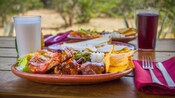 Two plates of traditional Mexican food with 2 beverages