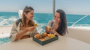 Dos mujeres en un catamarán disfrutando de un almuerzo juntas