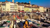 A firsherman sitting on a boat at a dock in Le Suquet, Cannes