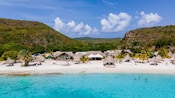 Una playa a lo largo de las orillas de Curazao con reposeras y sombrillas de paja