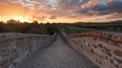 Uma ponte de pedra com árvores e o pôr do sol em Vulcos, onde hoje é o Lácio, na região central da Itália