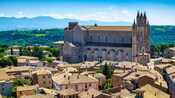 An historic village with a large Gothic cathedral surrounded by tiled roof buildings and a lush landscape